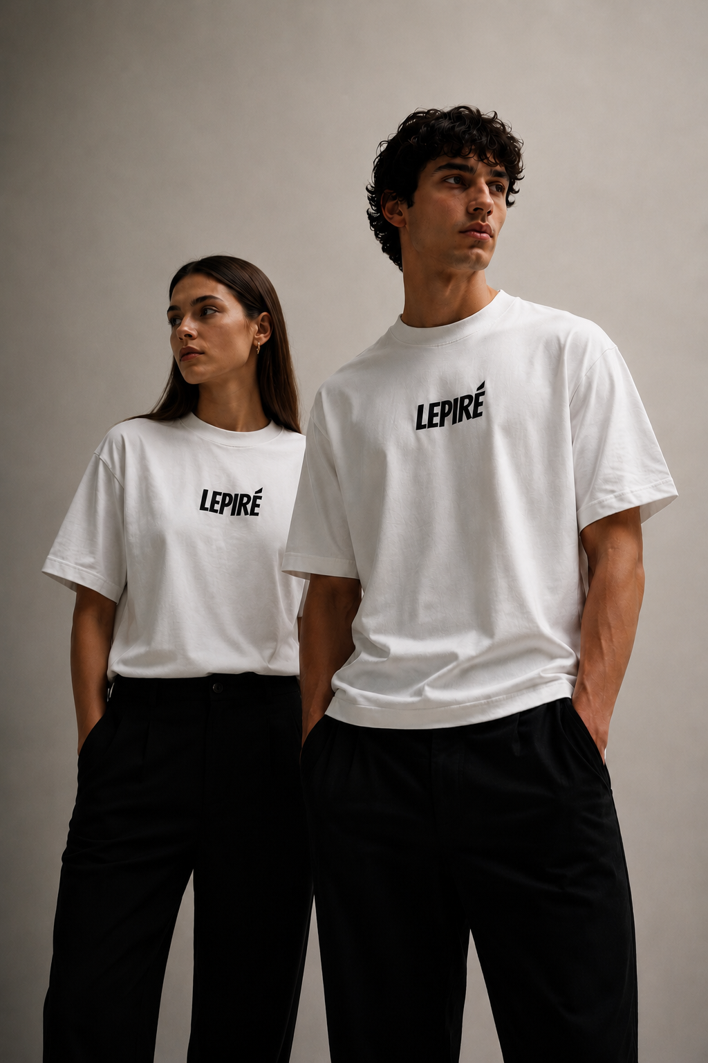 Twee modellen, een vrouw en een man, dragen beiden de witte LEPIRÉ oversized T-shirt tegen een neutrale achtergrond